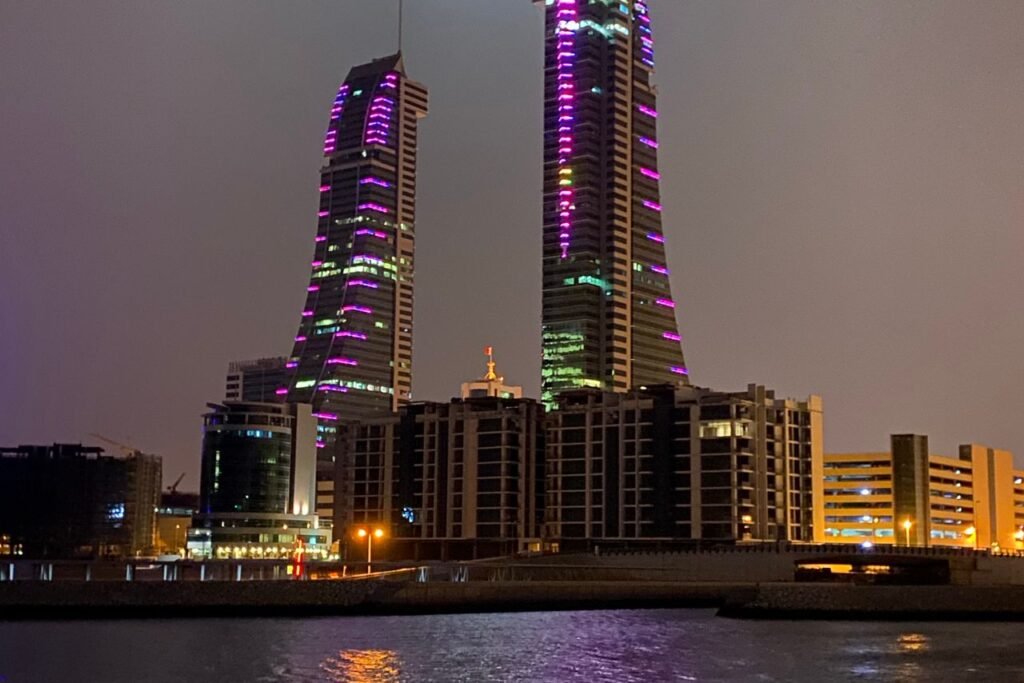 ناطحات سحاب المنامة المضيئة ليلاً منعكسة على الماء