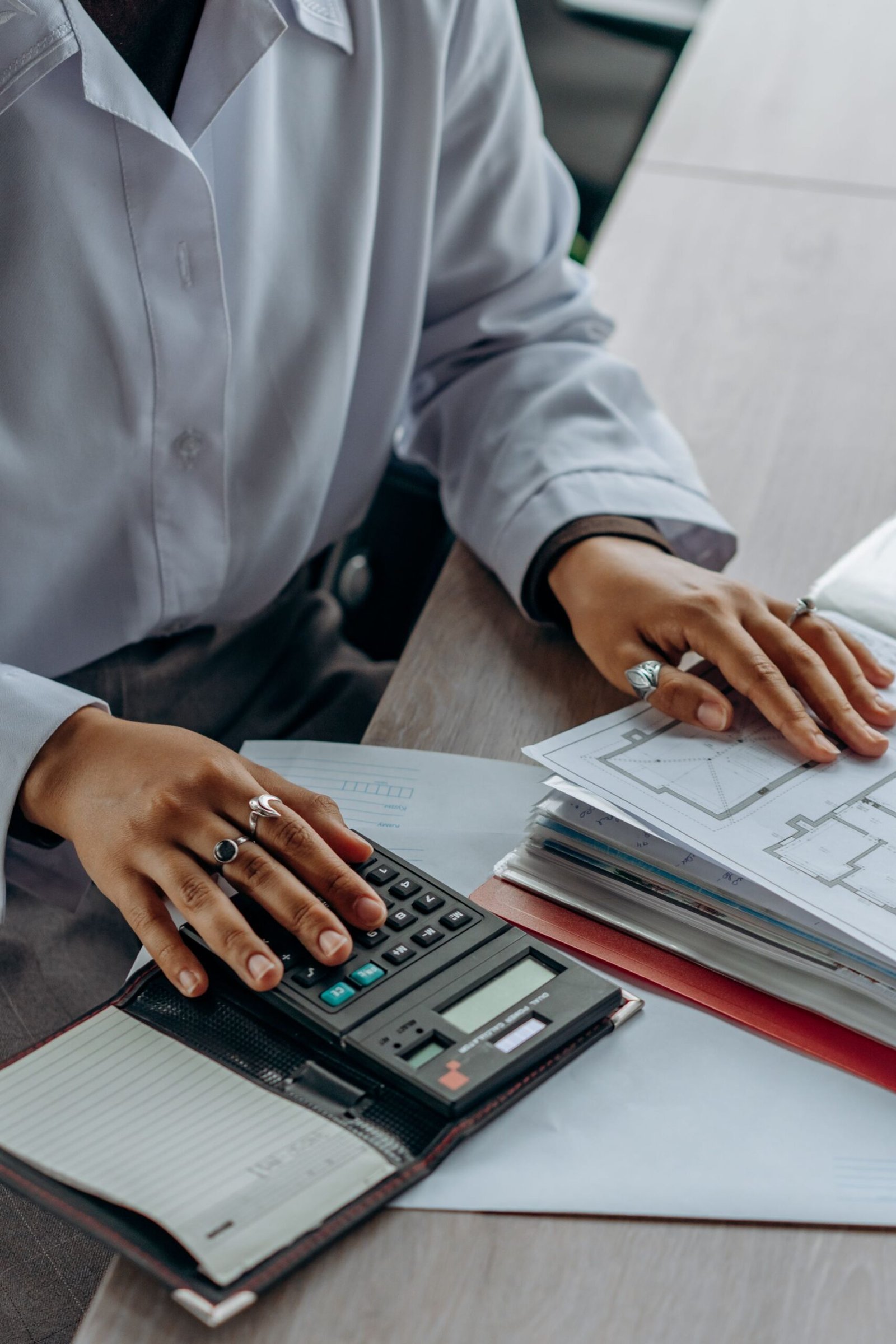 Hands working through paperwork and a calculator to compute a capital gain