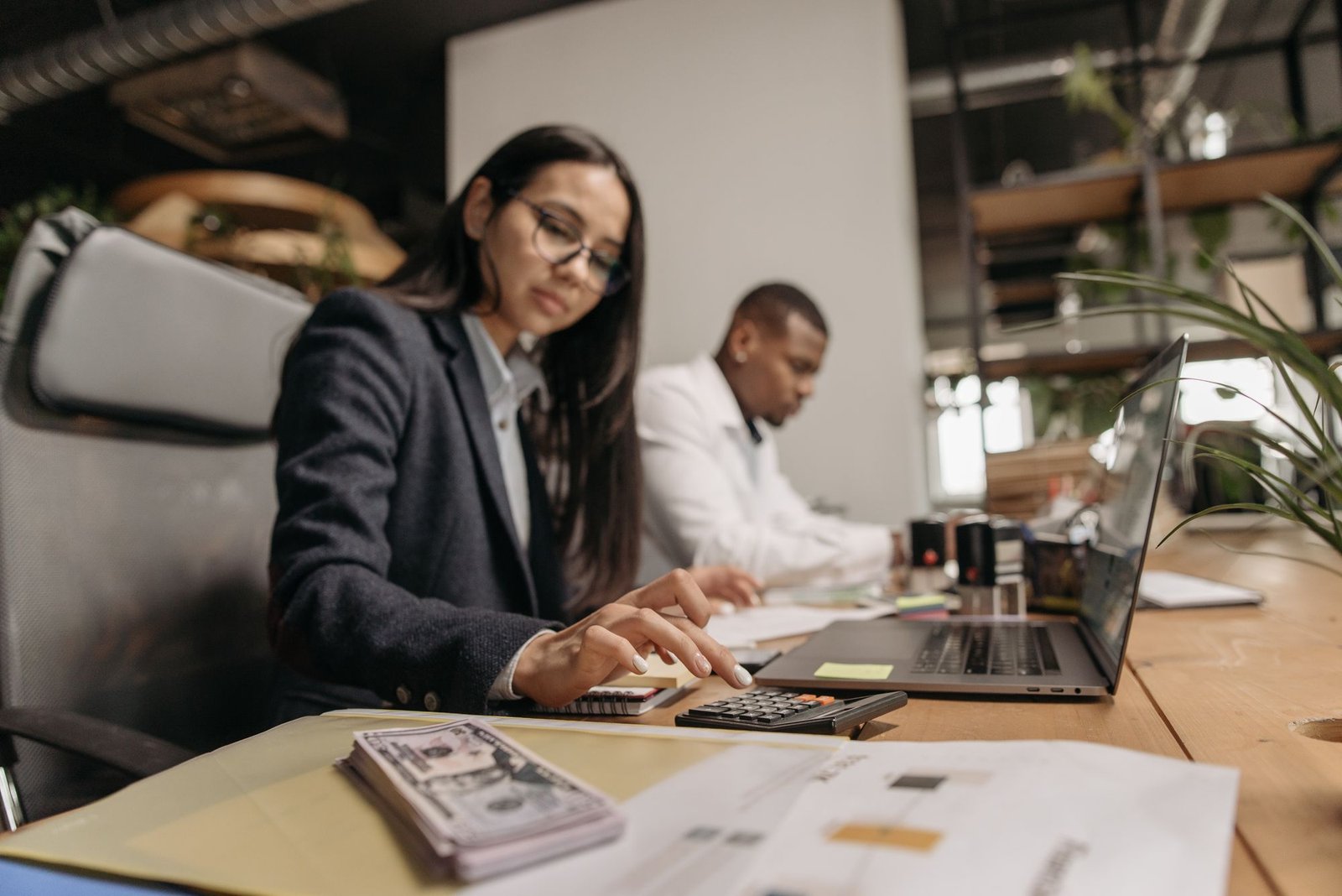 Two business professionals reviewing figures on a laptop in an office