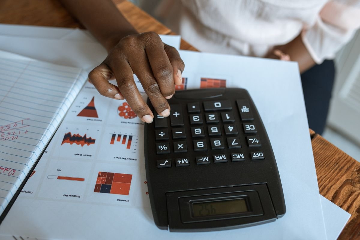 A person using a calculator beside financial charts, representing Self Assessment reporting of crypto capital gains
