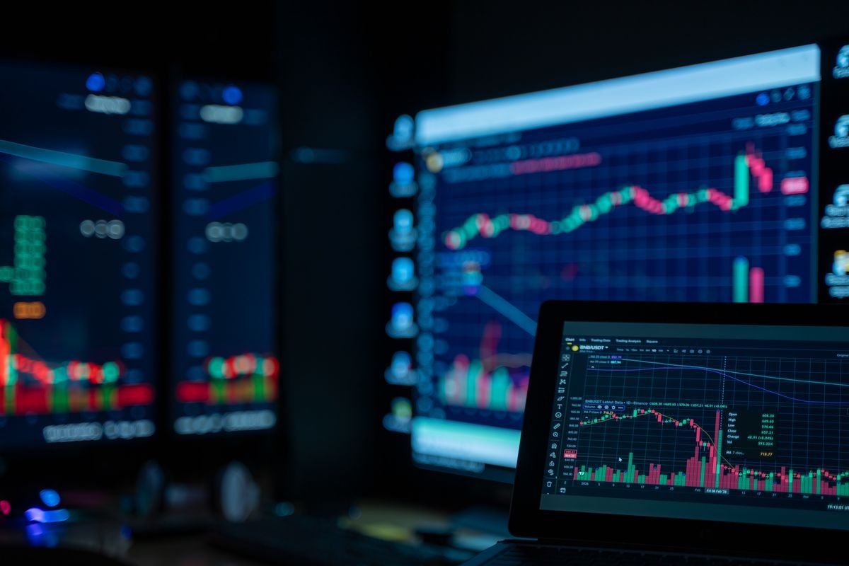 Multiple monitors showing market charts, representing high volume and automated crypto trading records