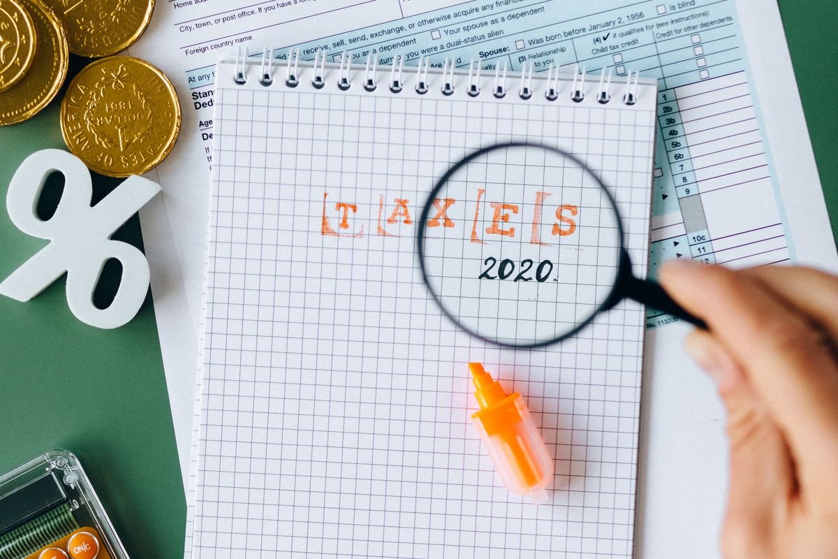 Tax forms, a magnifying glass and a calculator on a desk, representing an HMRC enquiry into crypto records