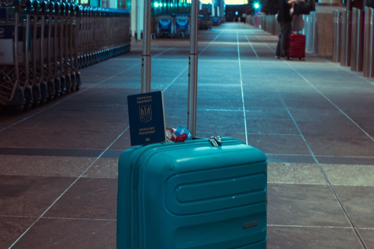A suitcase and passport in an empty airport terminal, representing leaving the UK while holding cryptoassets