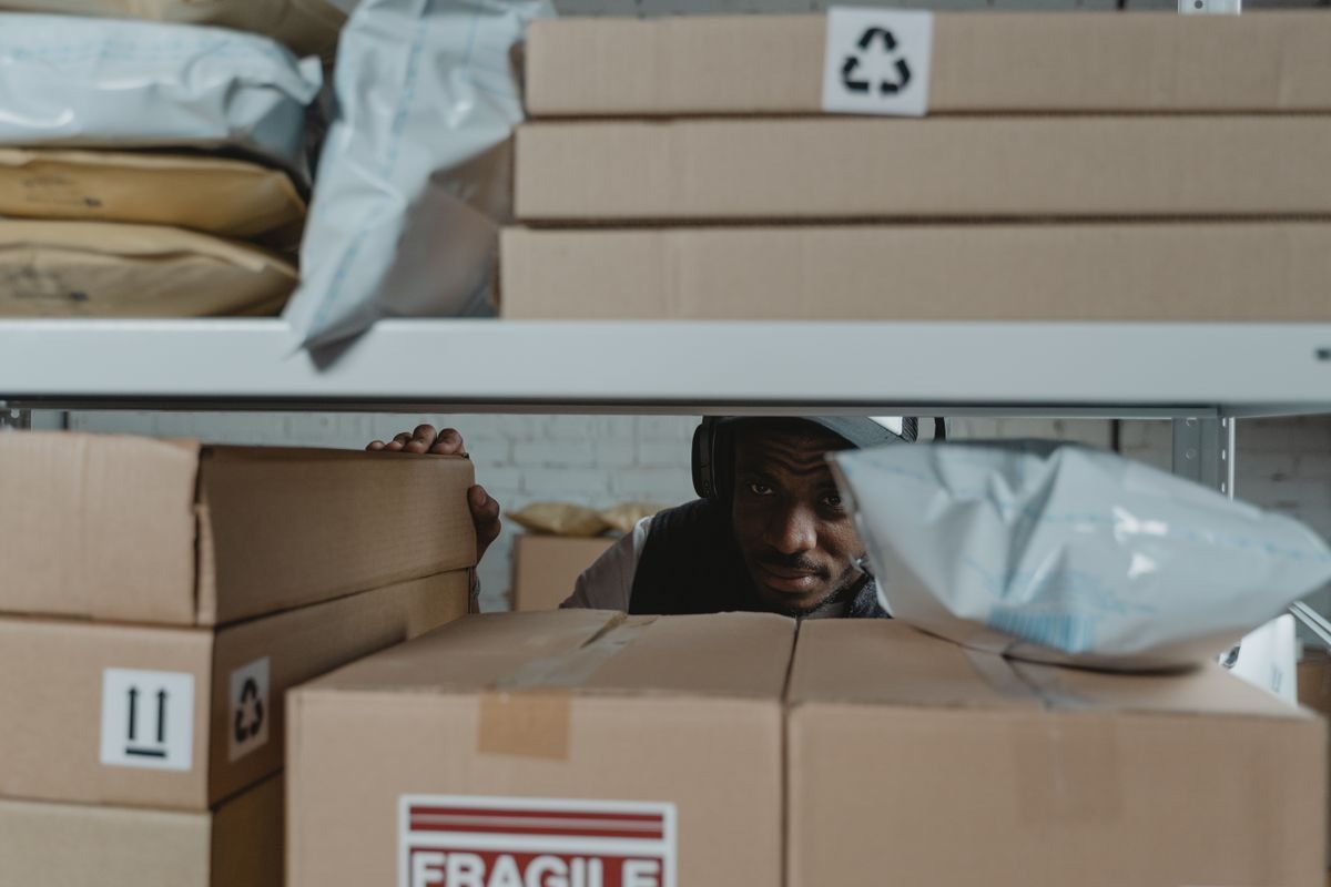 Worker checking labelled parcels on warehouse racking — fulfilment and stock valuation, TaxDigit