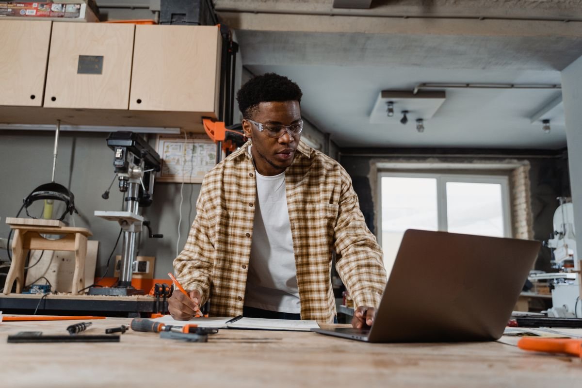 Tradesperson doing paperwork on a laptop in a workshop — CIS and limited company accounting, TaxDigit