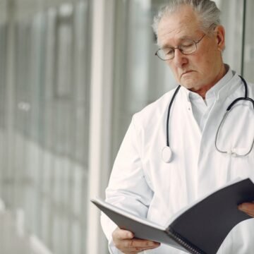 Locum doctor with a stethoscope reading a folder