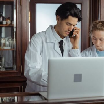 Pharmacist working at a laptop behind a pharmacy counter