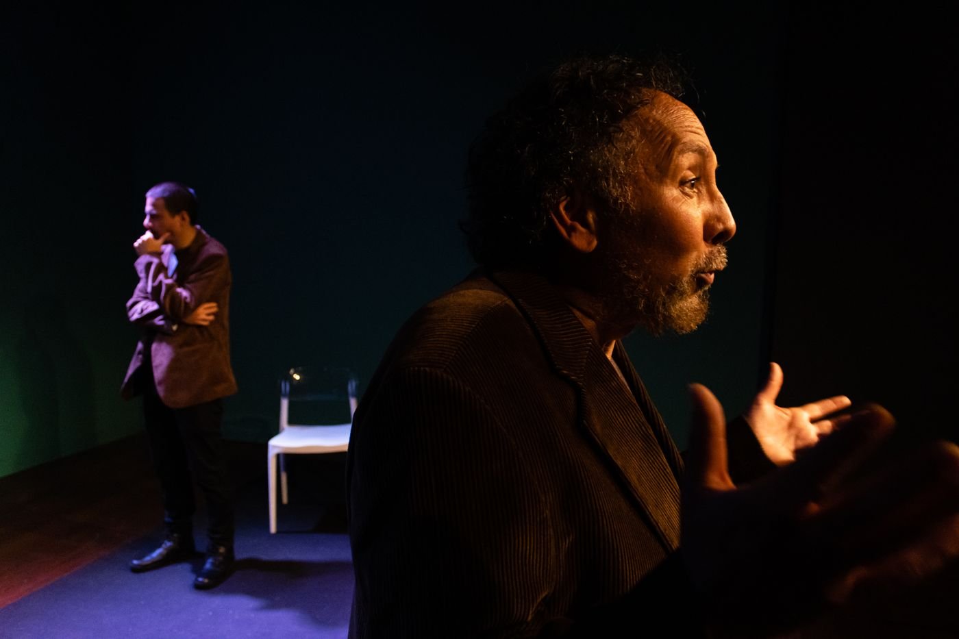 Two actors performing a scene on a lit theatre stage