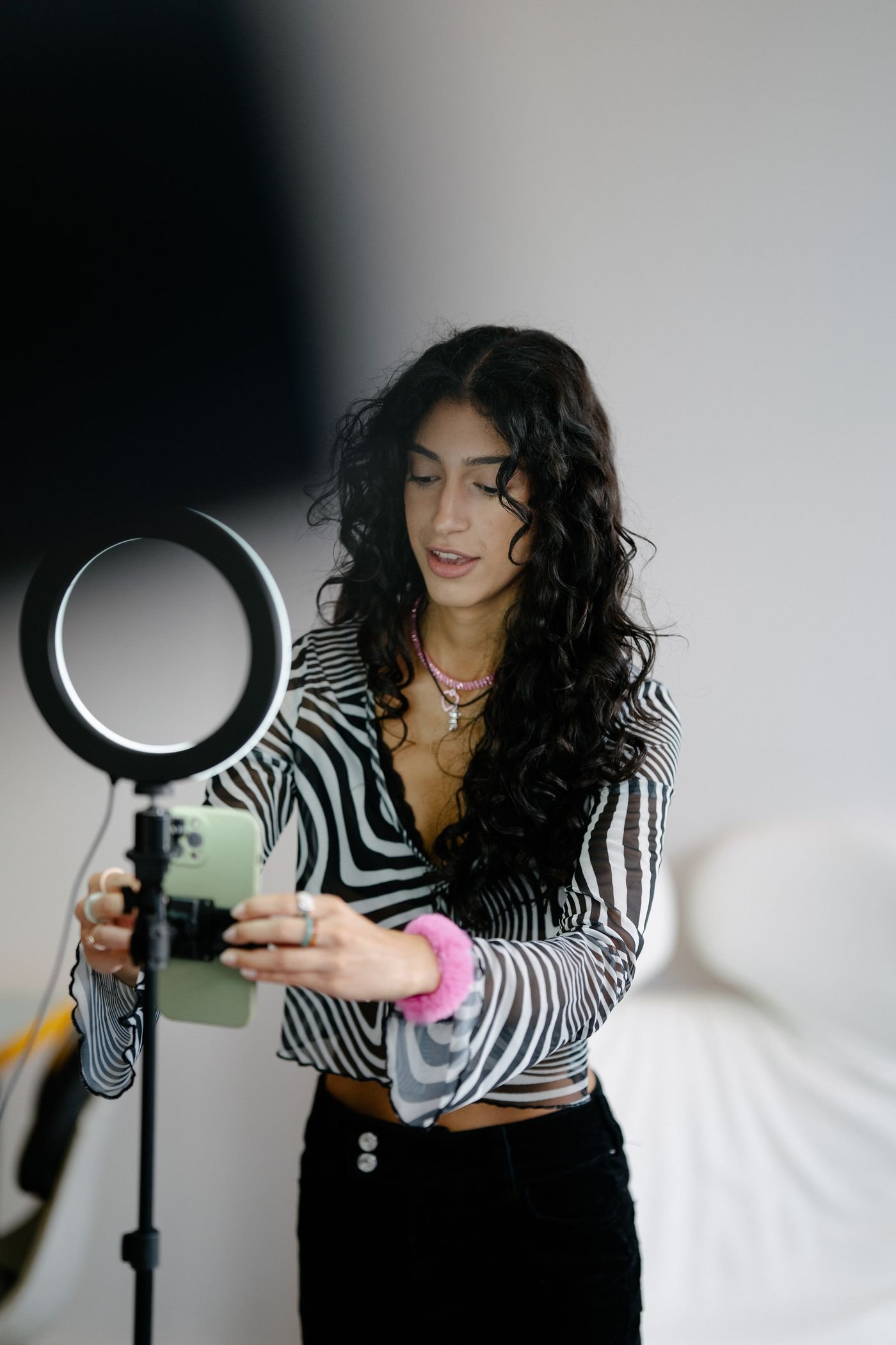 Content creator fixing a smartphone to a tripod beside a ring light in a home studio