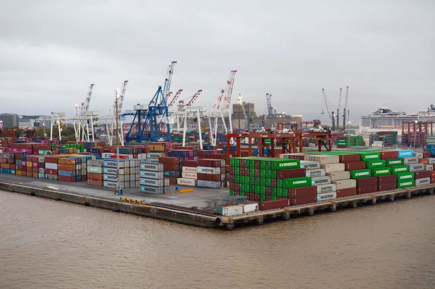 Stacked shipping containers and cranes at a busy freight port