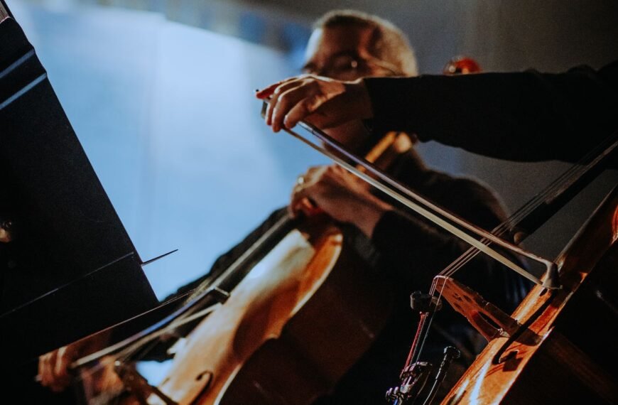 Cellist performing on stage with an orchestra under theatre lighting — Orchestra Tax Relief, TaxDigit