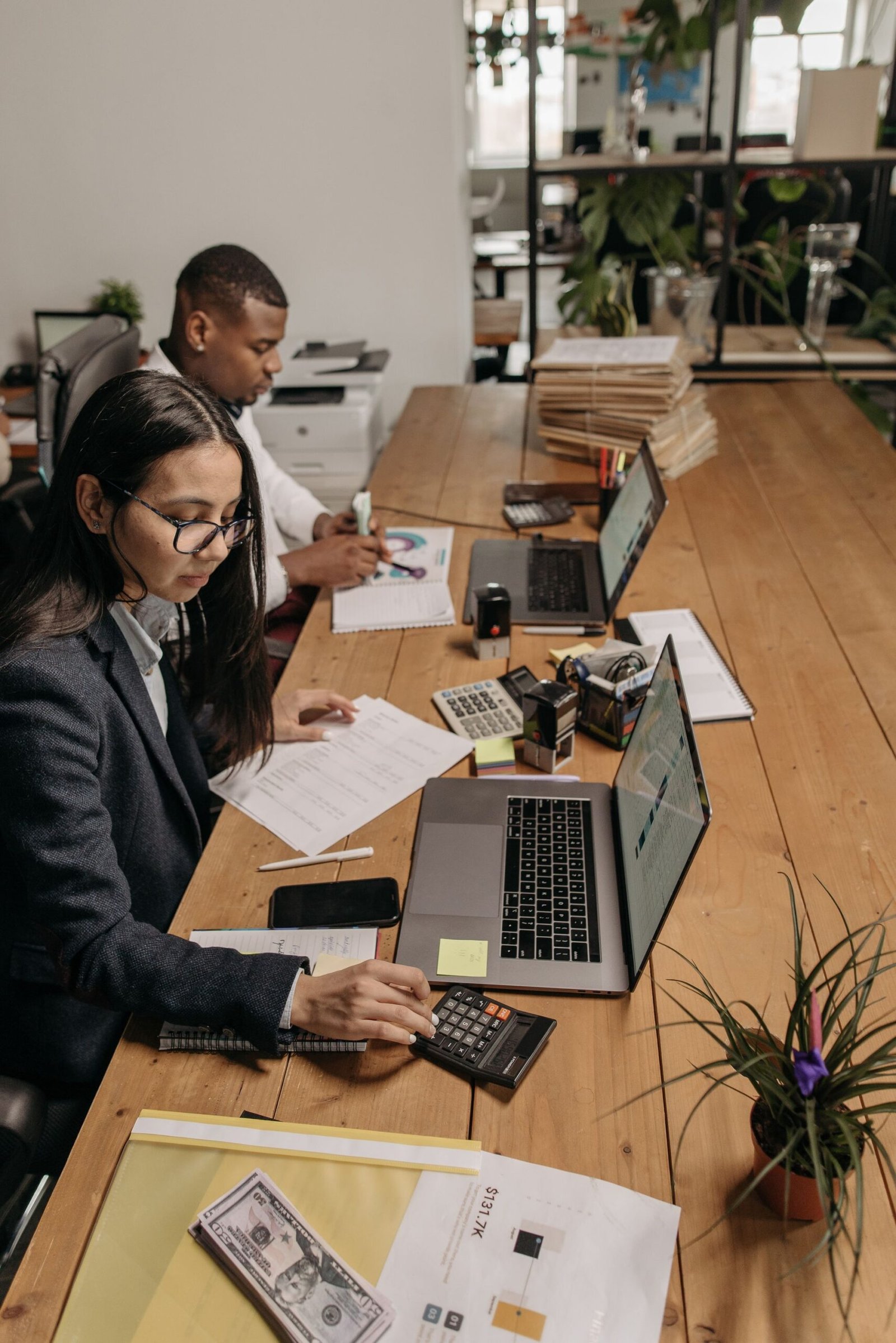 Two accountants reconciling records together on laptops in an office